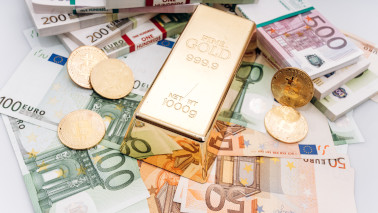 Goldbarren und Goldmünzen liegen auf Euro-Banknoten.