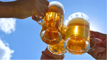 Drei Personen stoßen mit drei Biergläsern an. Im Bildausschnitt sieht man nur die Hände und Gläser.