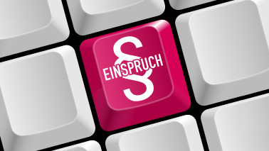 Nahaufnahme einer Tastatur. Eine der Tasten ist eingefärbt und trägt die Aufschrift "EINSPRUCH" dahinter ist das Symbol für Paragraph zu sehen..