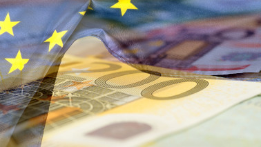 Ein Foto von Geldscheinen wird von einer Europaflagge überlagert.
