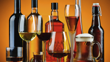 Verschiedene Gläser mit passenden alkoholischen Getränken stehen nebeneinander, dahinter steht eine Reihe mit dazugehörigen Flaschen.